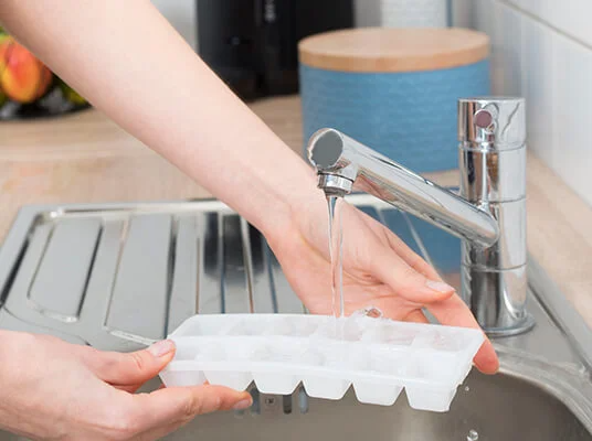 Eine Eiswürfelschale mit Wasser füllen.