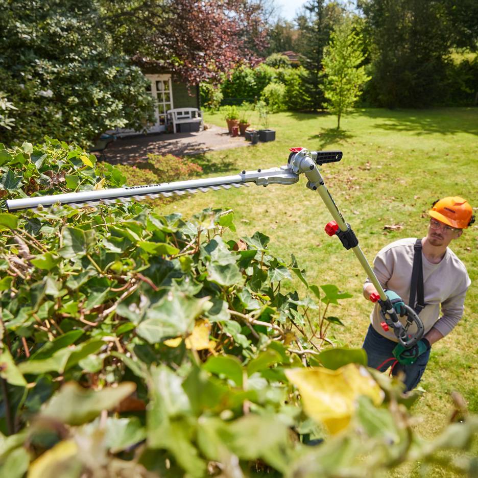 Mann schneidet Hecke mit Parkside Teleskop-Heckenschere.