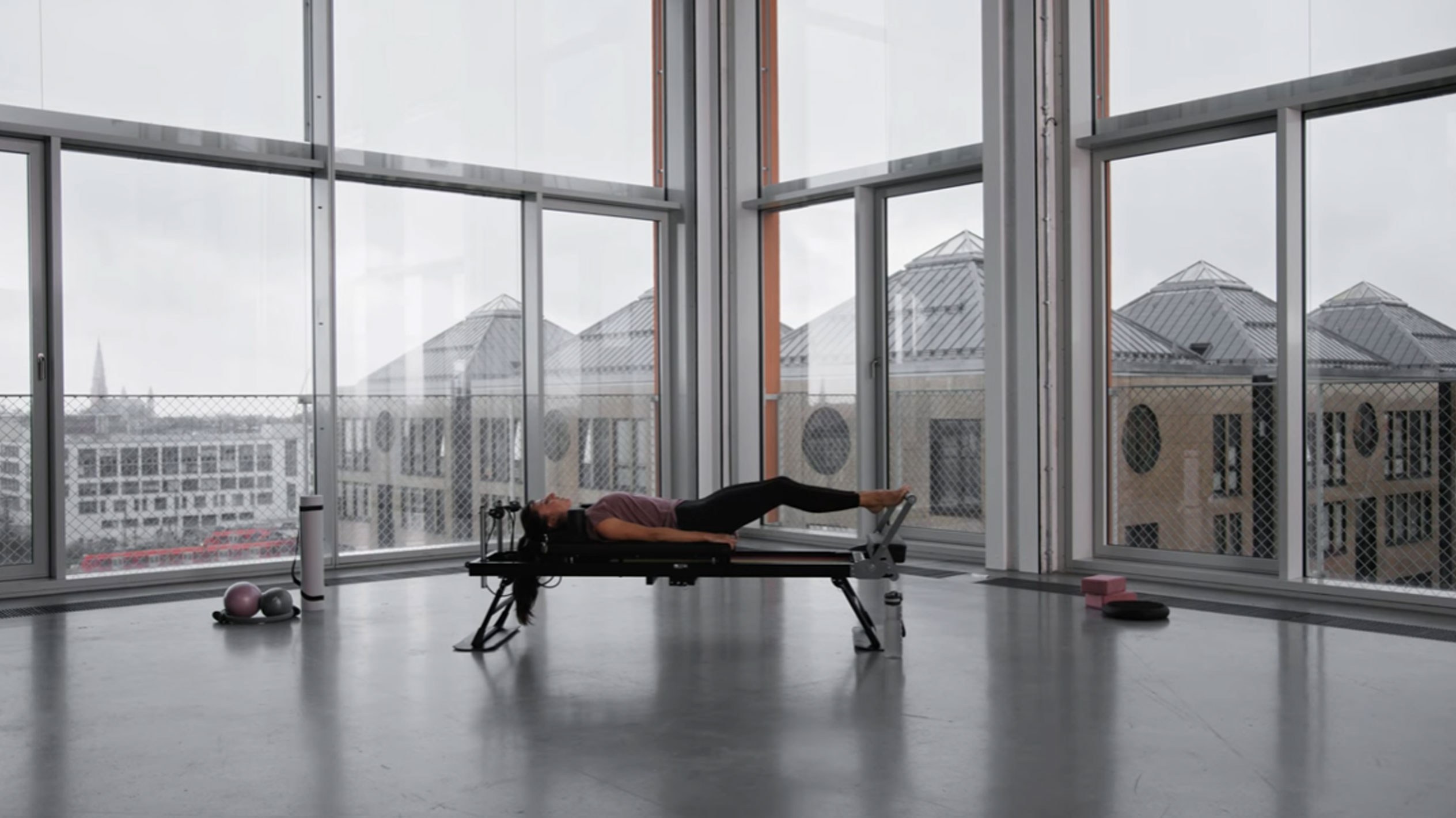 Frau macht Pilates in modernem Studio mit Stadtblick.