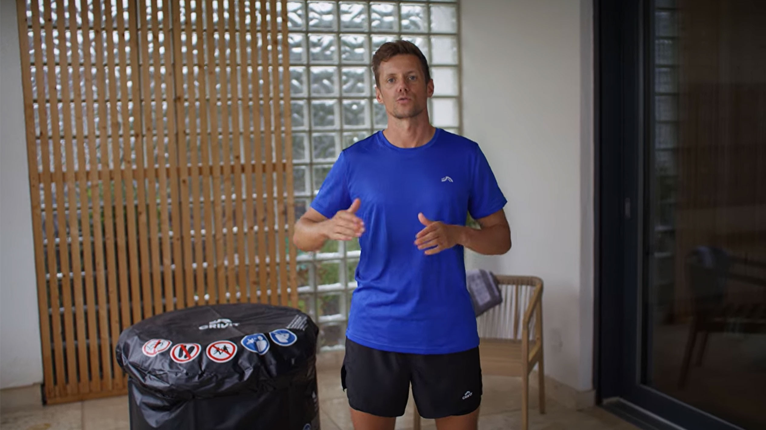 Mann in blauem T-Shirt und schwarzen Shorts, neben einer schwarzen Whirlpool-Abdeckung.