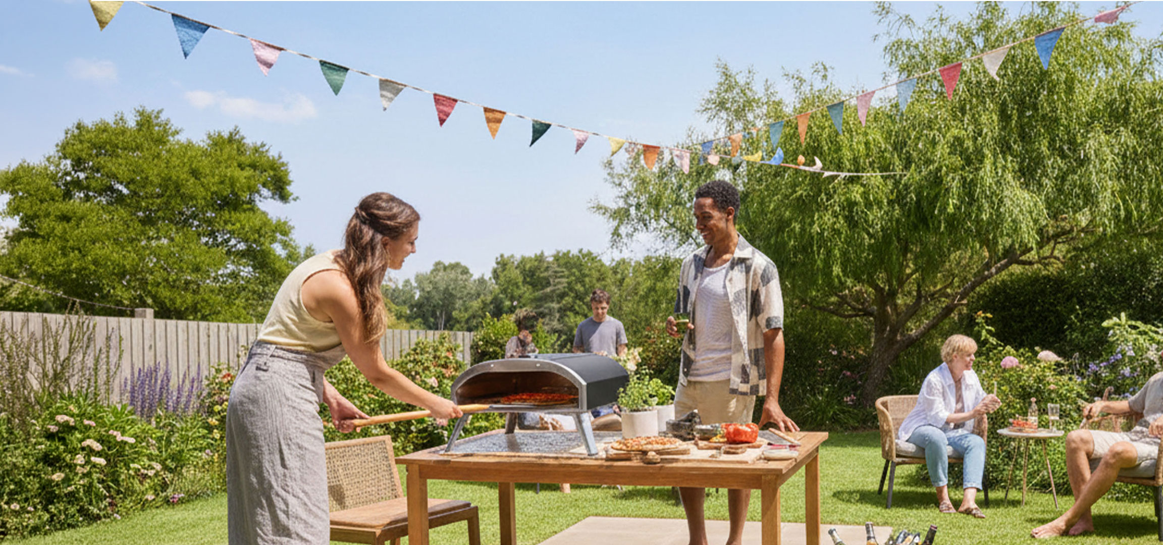 Freundesgruppe bereitet Pizza in einem Outdoor-Ofen zu und genießt einen Sommertag.