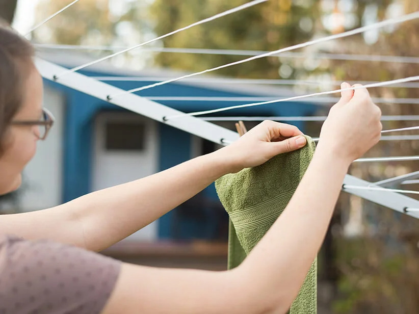 Eine Frau hängt Handtücher auf die Wäscheleine.