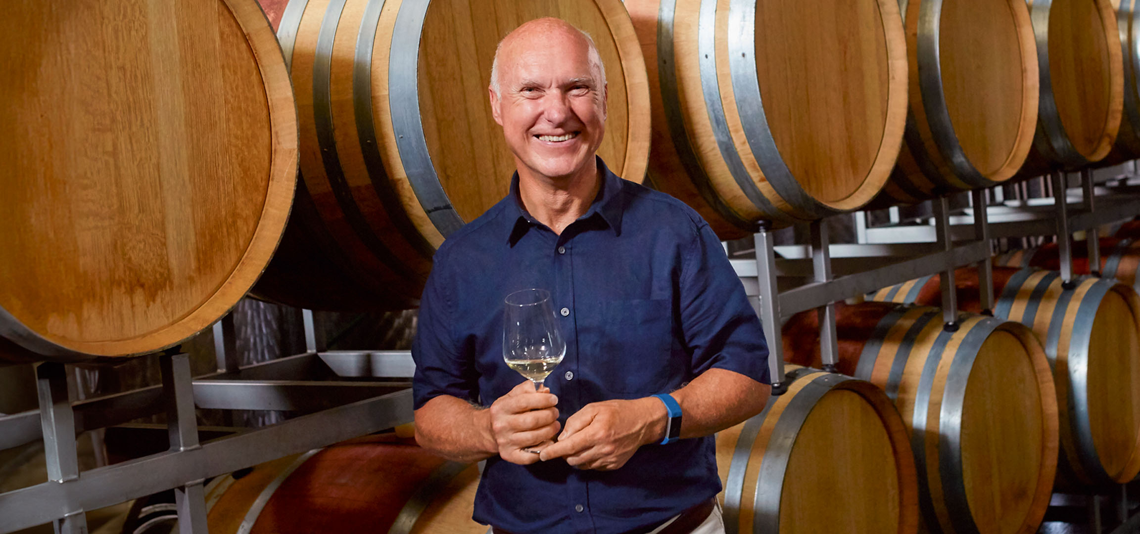 Weinfässer und ein Mann mit einem Glas Wein.