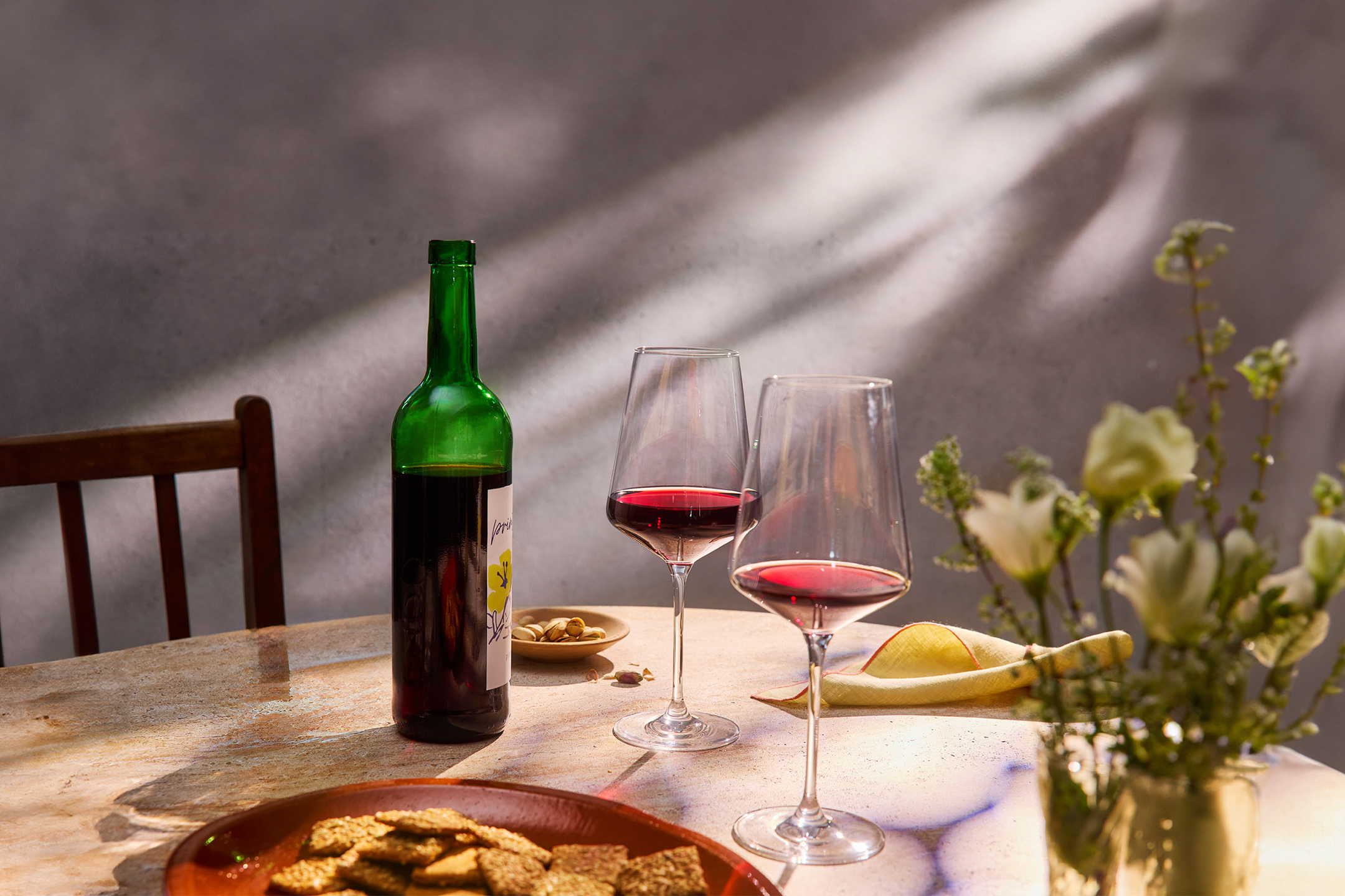 Wein, Cracker und Blumen auf einem Tisch.