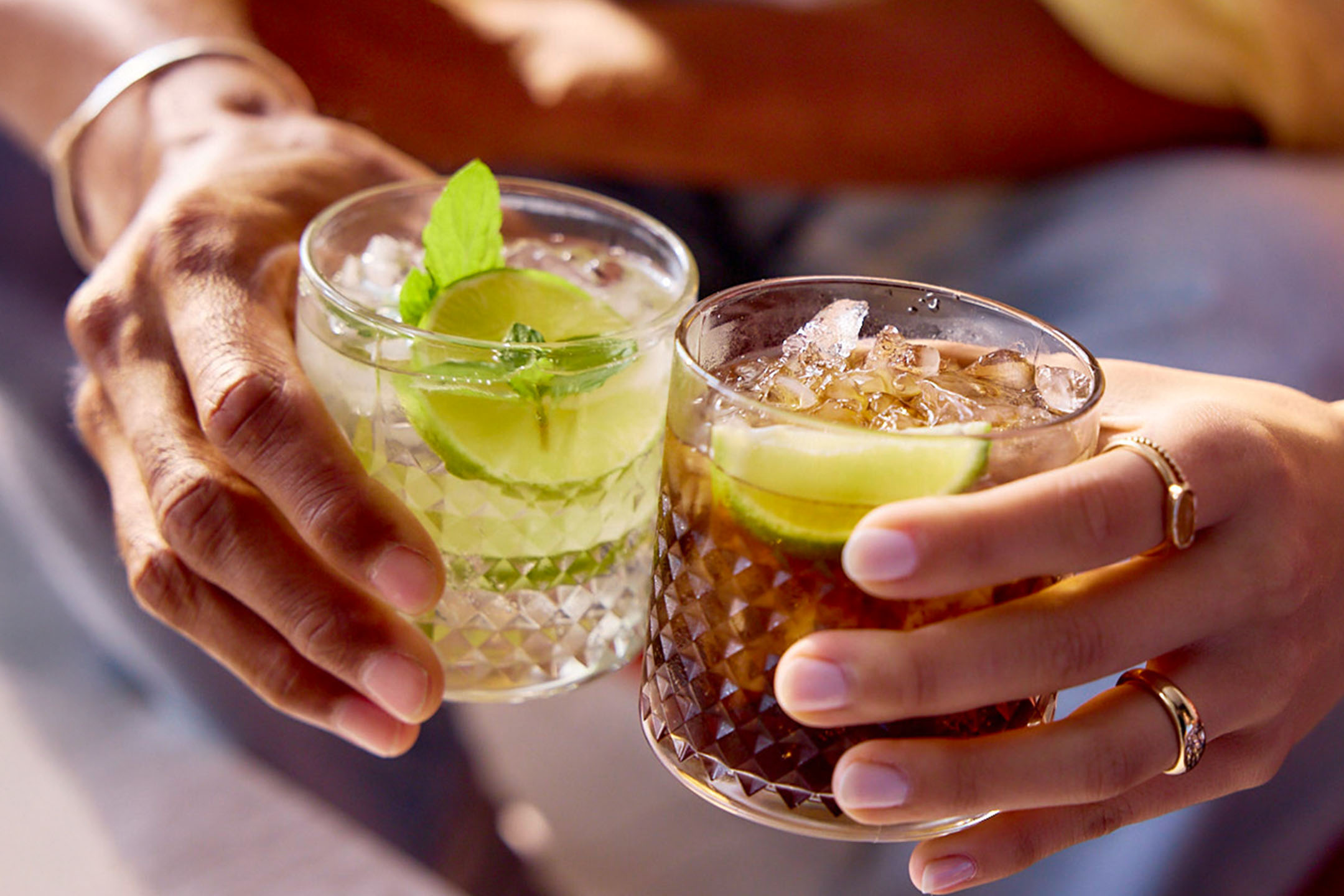Zwei Cocktails: einer mit Minze und Limette, einer mit Cola und Limette.