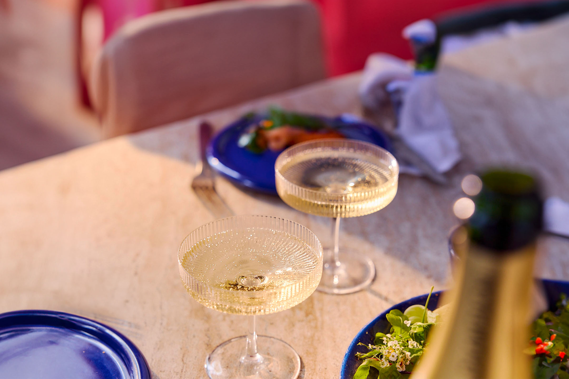 Champagner und Salate auf blauen Tellern.