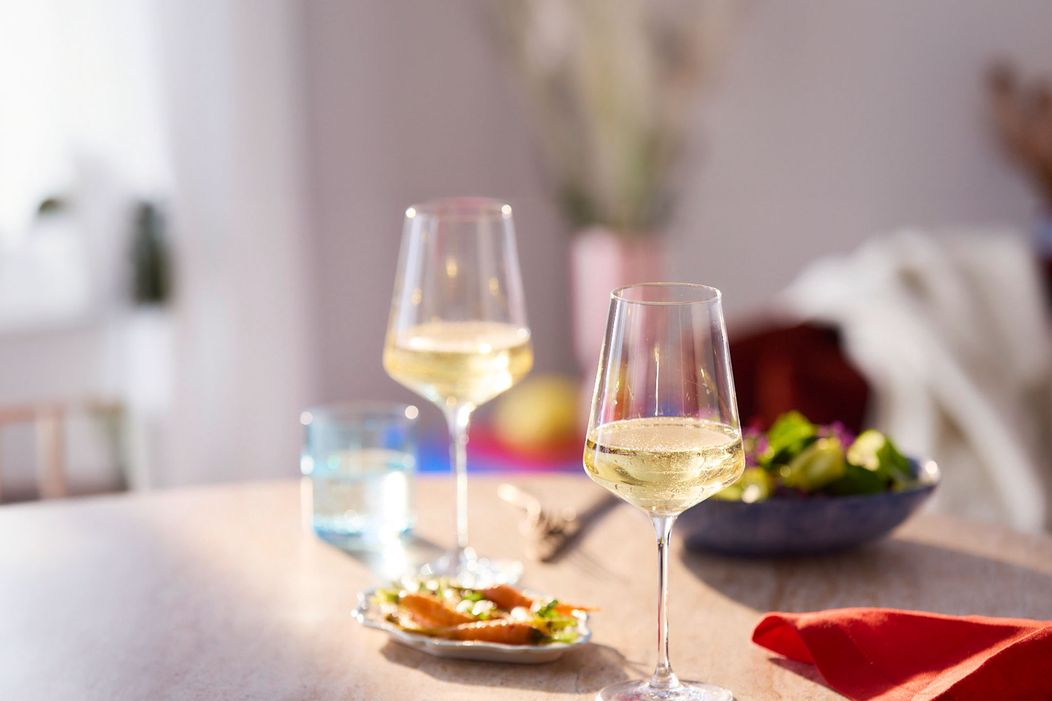 Wein, Salat und Karotten auf einem Tisch.