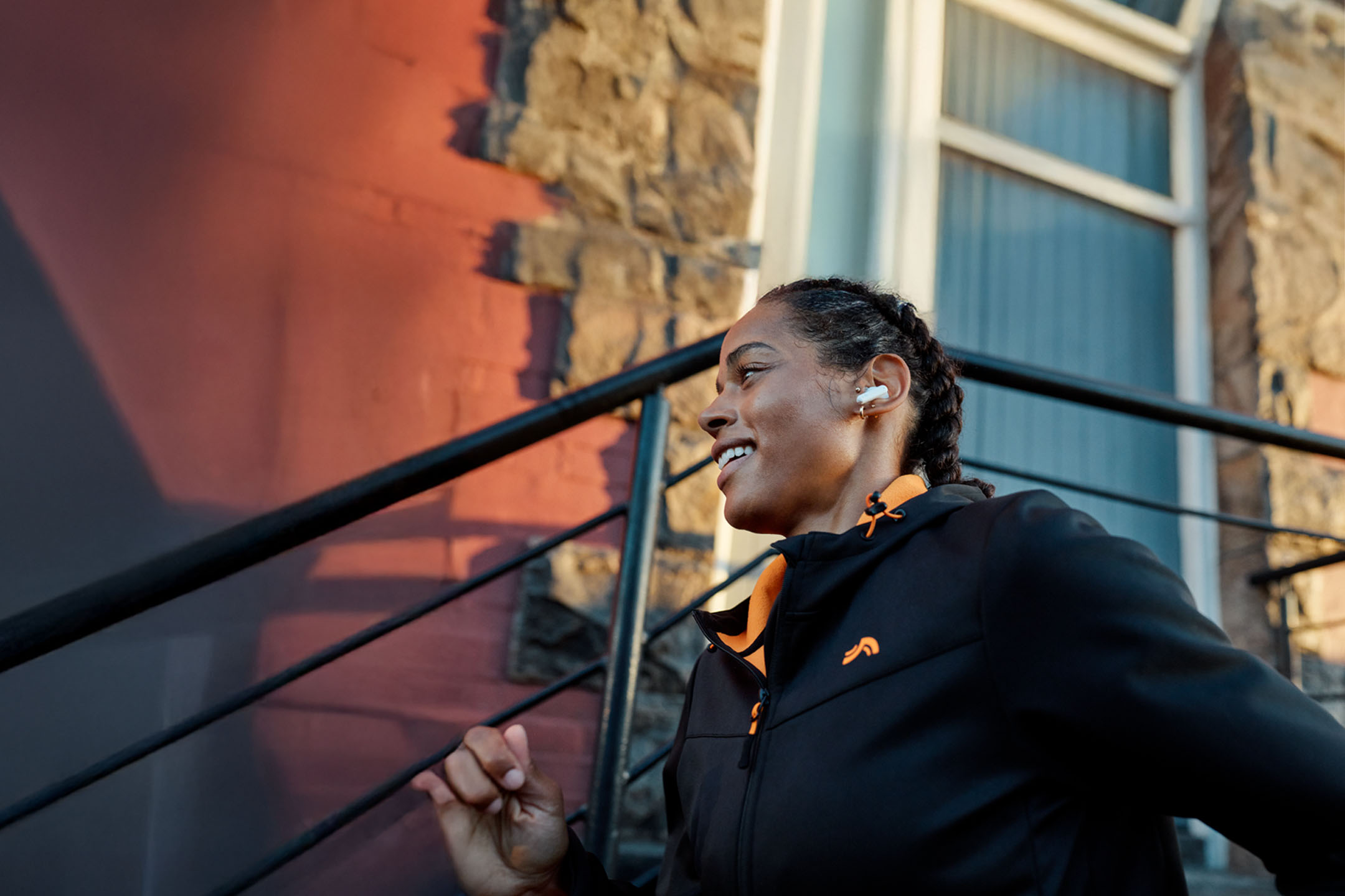 Frau joggt mit Kopfhörern, trägt Jacke.