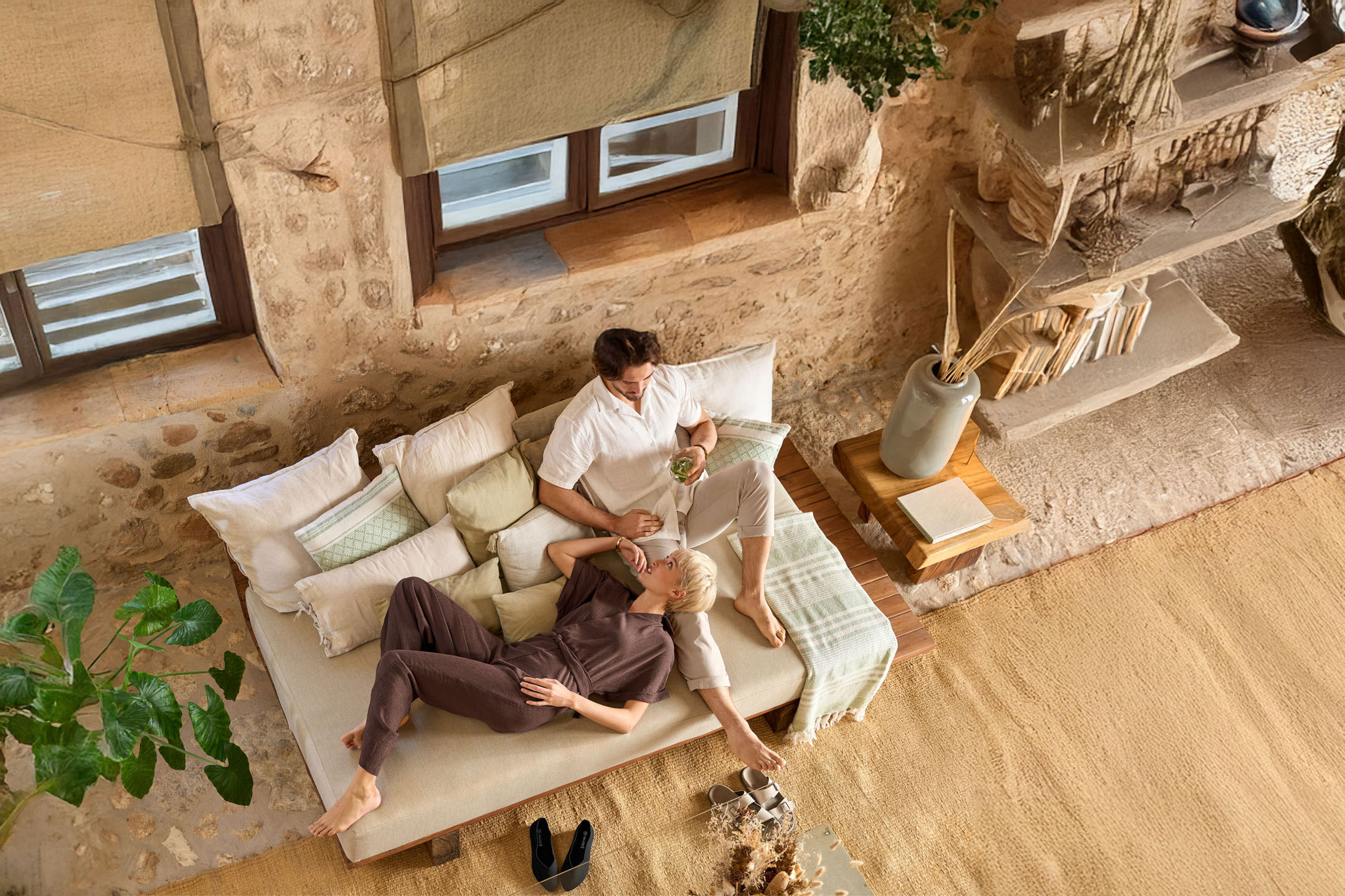 Paar entspannt auf einer Couch in erdfarbenen Klamotten und Accessoires.