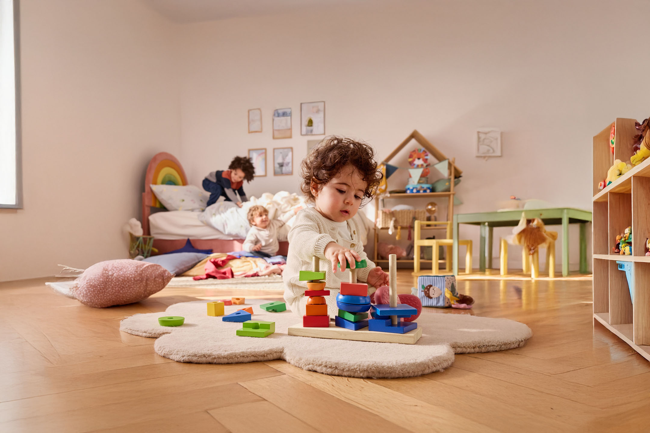 Ein kleines Kind spielt mit einem Holzbaukasten in seinem Zimmer.
