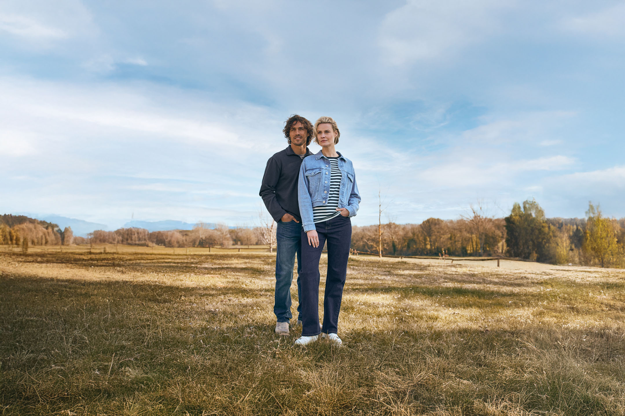 Paar in Jeansjacken in ländlicher Umgebung.