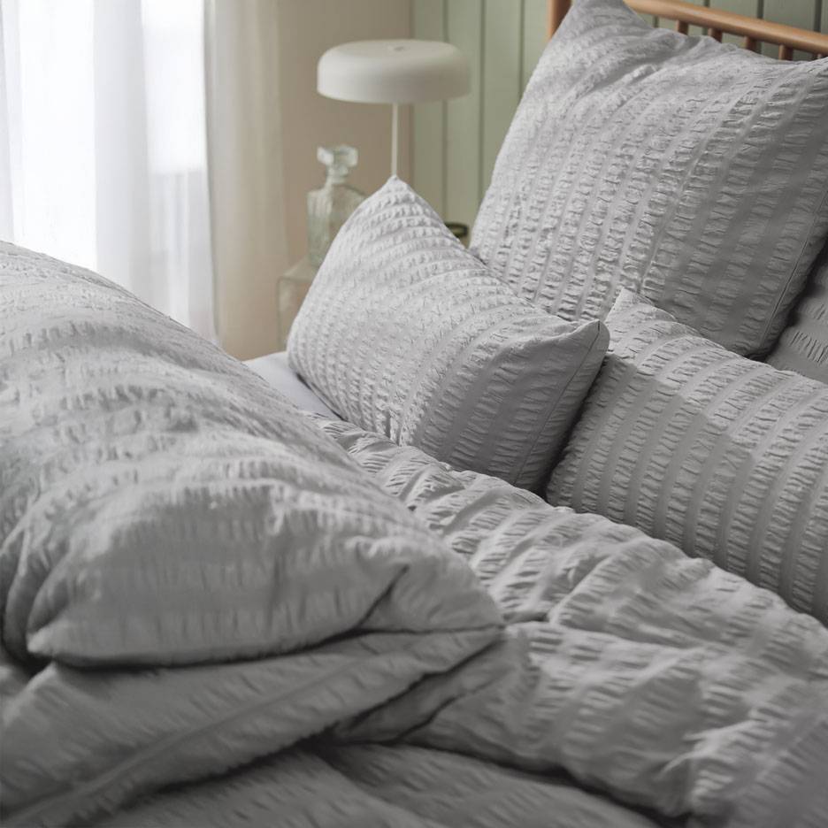 Graues Bettwäsche-Set mit strukturierten Kissen.