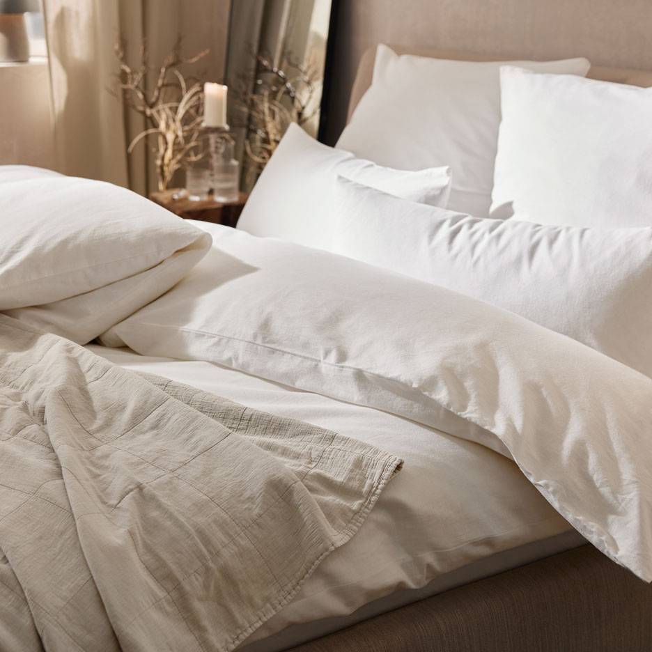 Weiße Bettwäsche, Kissen und eine Decke.