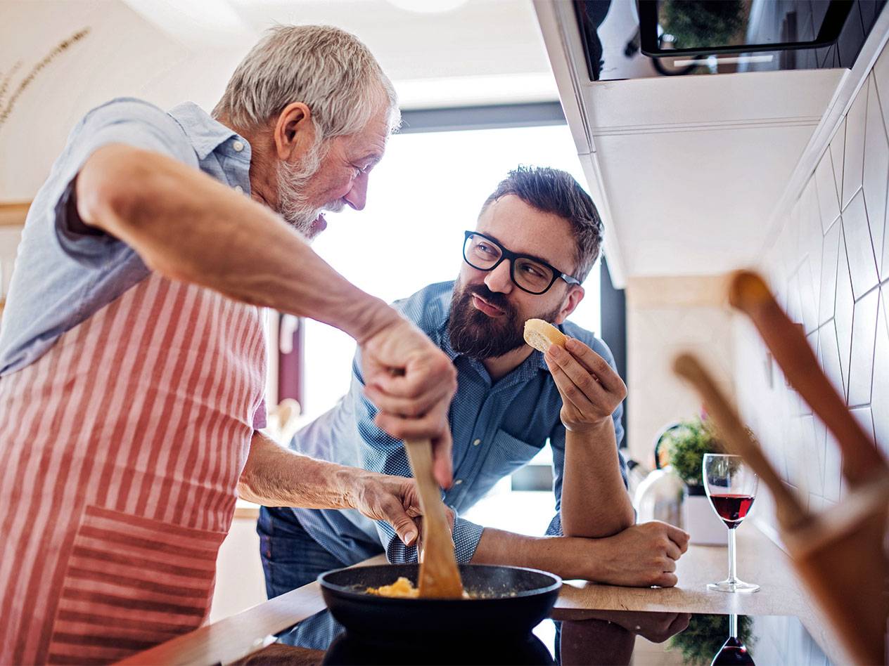 Vater und Sohn kochen gemeinsam Frühstück: Eier und Brot.