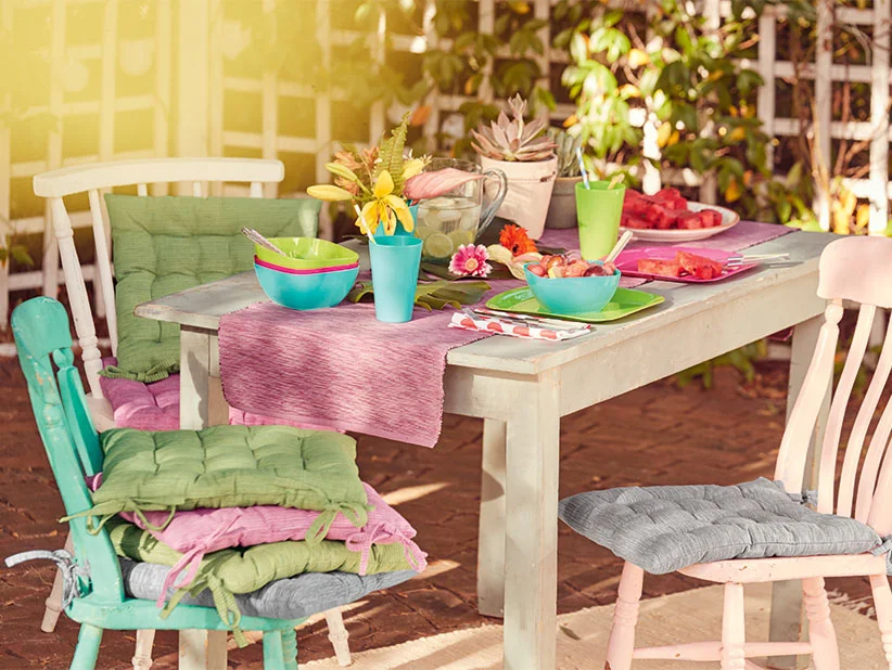 Gartenmöbel, bunte Schüsseln und Kissen.