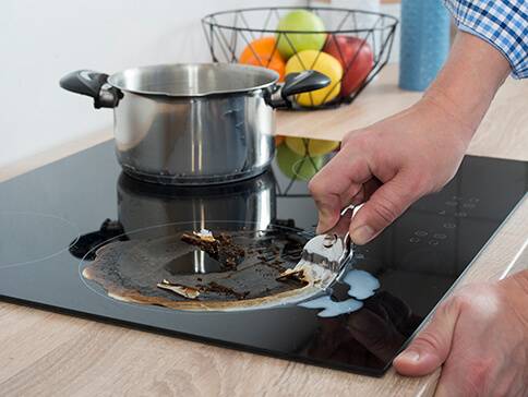 Kochfeldreinigung: angebranntes Essen und Edelstahltopf.