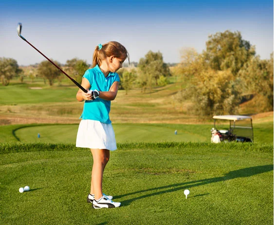 Mädchen spielt Golf, Schläger und Bälle sichtbar.