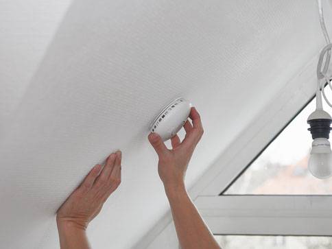 Montage eines Rauchmelders an der Decke.