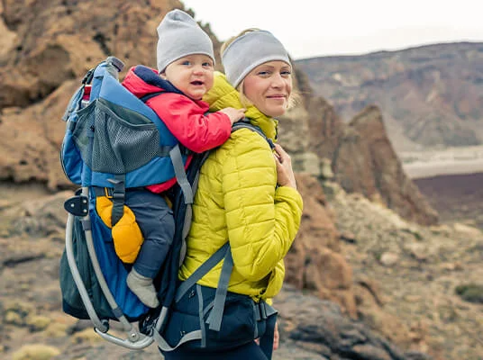 Mutter trägt Baby in Rucksack in der Natur.