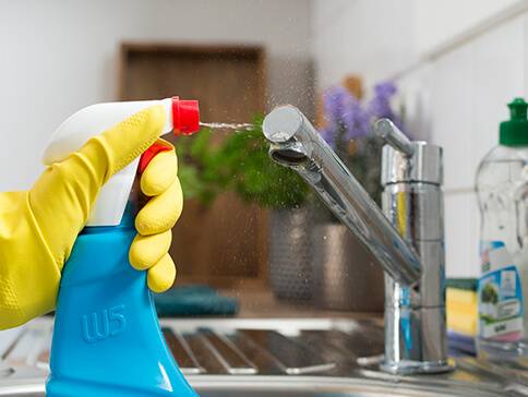 WC-Reiniger wird auf den Wasserhahn gesprüht.