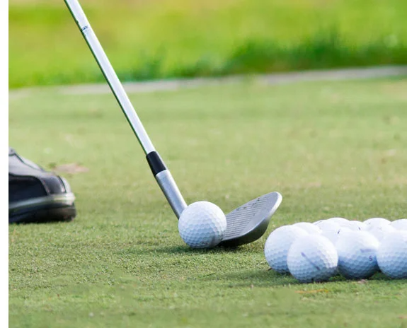 Nahaufnahme von Golfschläger und Golfbällen auf dem Grün.