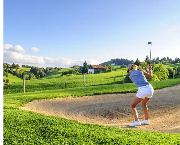 Golferin übt im Bunker in schöner Landschaft.