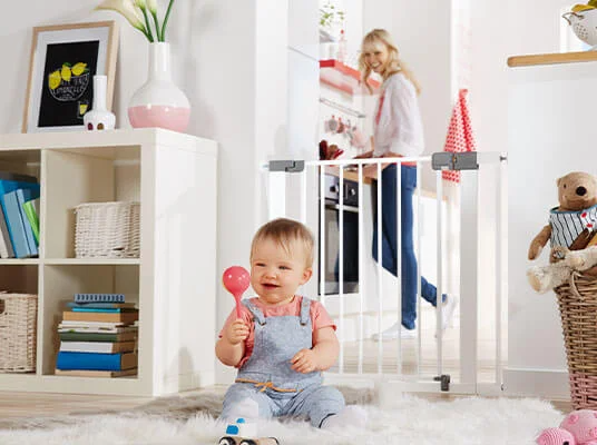 Baby, Treppenschutzgitter und Spielzeug.
