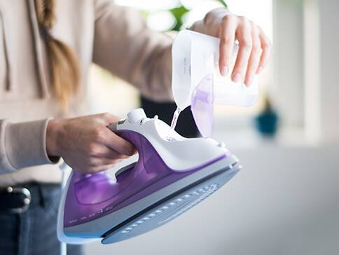 Wasser wird in ein Bügeleisen gefüllt.