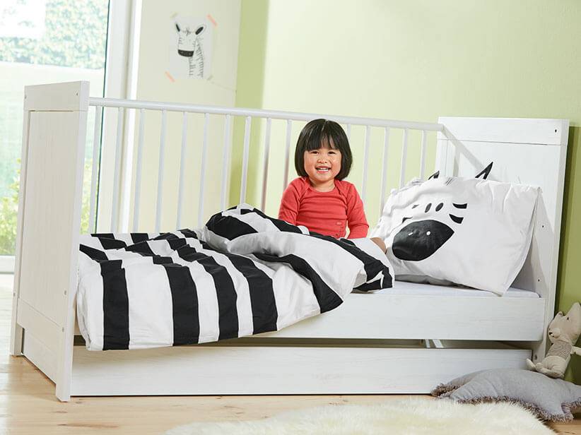 Weißes Babybett, schwarz-weiß Bettwäsche, Zebra-Muster.