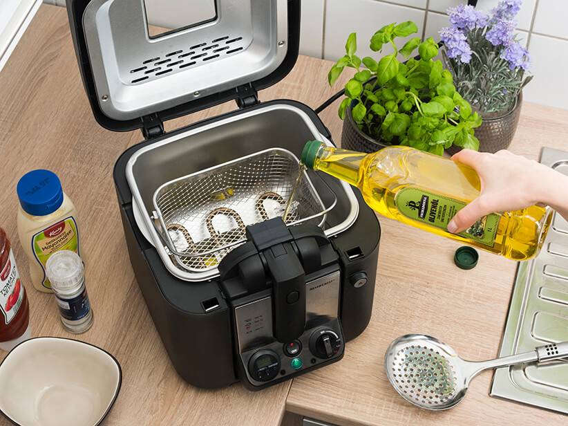 Öl wird in eine Friteuse mit Korb gegossen.