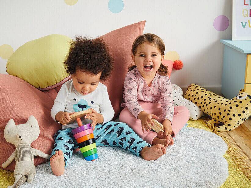 Kleinkinder spielen mit Holzspielzeug und tragen süße Kleidung.