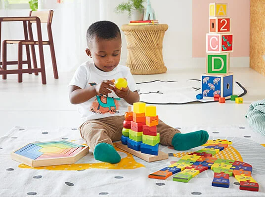 Kind spielt mit Holzwürfeln und Zahlenpuzzle.