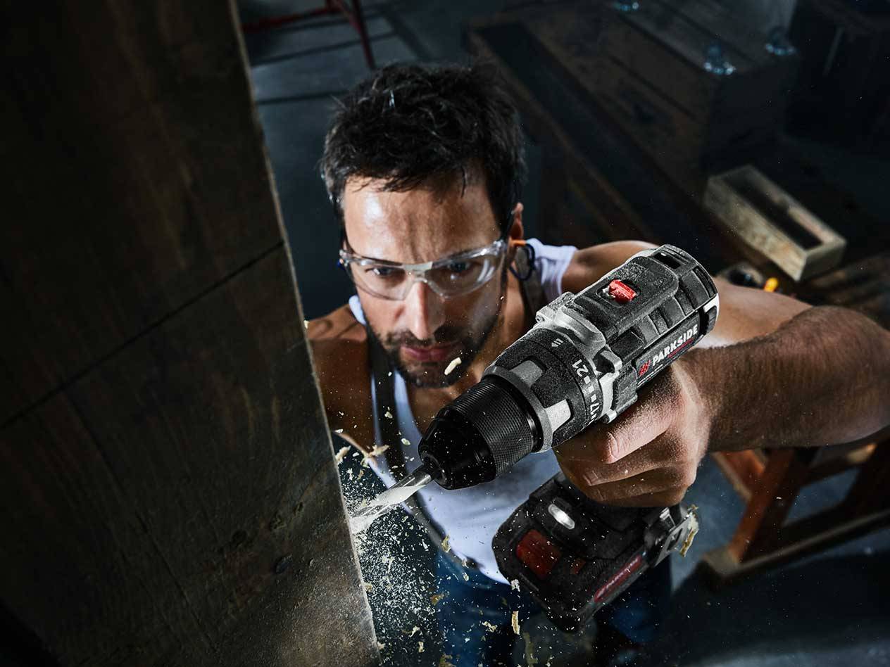 Mann bearbeitet Holz mit Parkside Bohrmaschine.