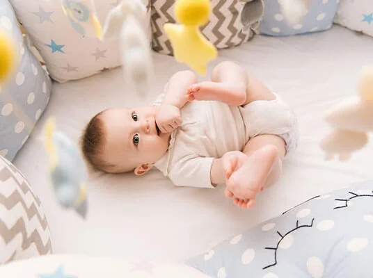 Baby spielt mit süßen Plüschtieren und Kissen.