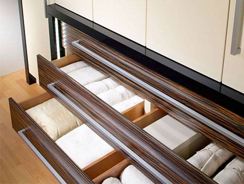 Elegante Schubladen aus dunklem Holz mit Textilien.