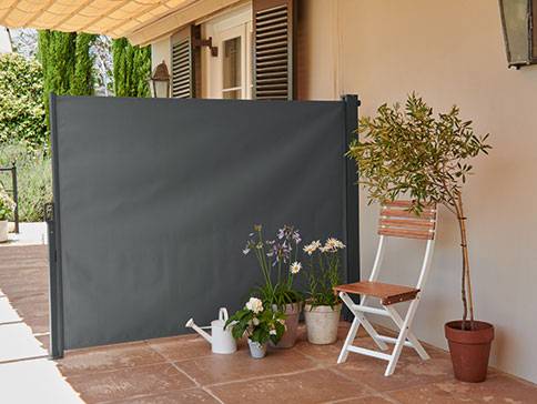 Grauer Sichtschutz und Gartenstuhl.