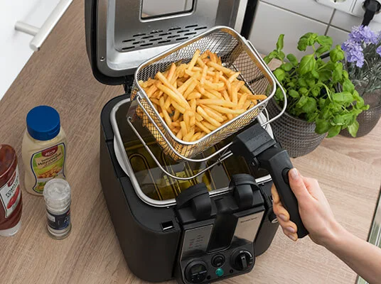 Fritteuse mit Frittierkorb und Pommes frites.
