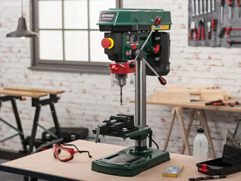 Bohrmaschine, Werkbank und Schutzbrille.