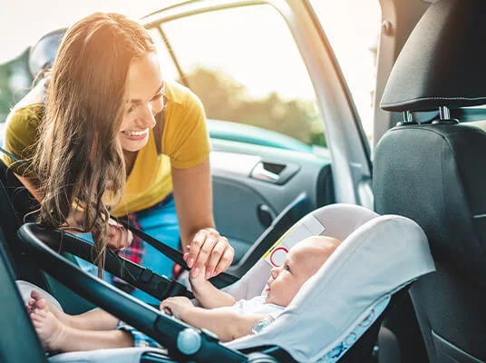 Eine Mutter setzt ihr Baby in einen Autositz.