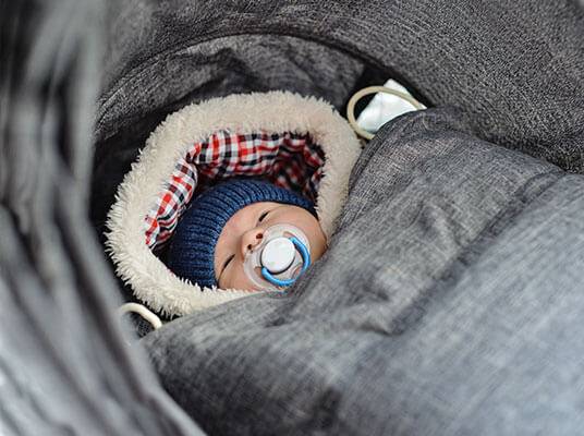 Baby schläft in einem warmen Schlafsack im Kinderwagen.