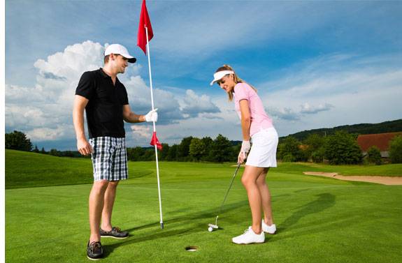 Golfspielendes Paar auf dem Grün; Schläger und Fahne sichtbar.