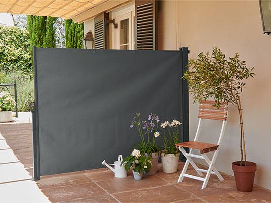 Graue Terrassenabschirmung und Gartenstuhl.