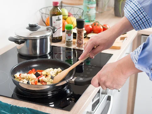 Gebratenes Gemüse in der Pfanne und Topf auf dem Herd.