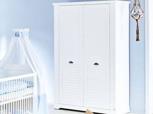 Weißer Kleiderschrank und Babybett.