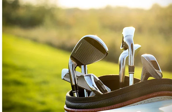 Golftasche mit Schlägern auf einem sonnigen Golfplatz.