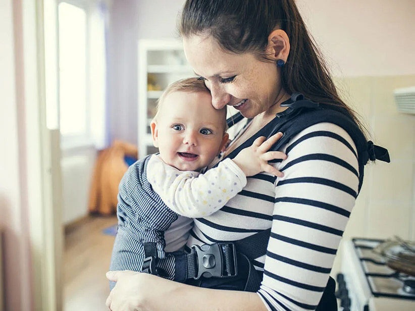 Eine Mutter trägt ihr Baby in einer Tragehilfe.