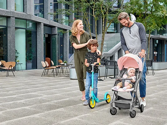 Kinderwagen, Roller und Kinder draußen.