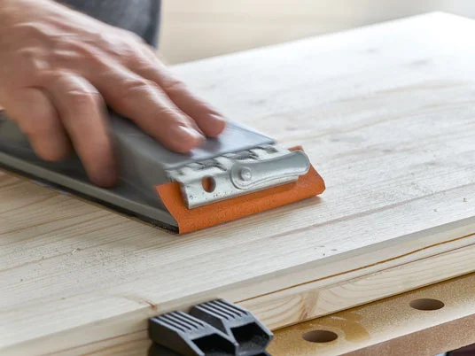 Holz wird mit Handschleifer bearbeitet.