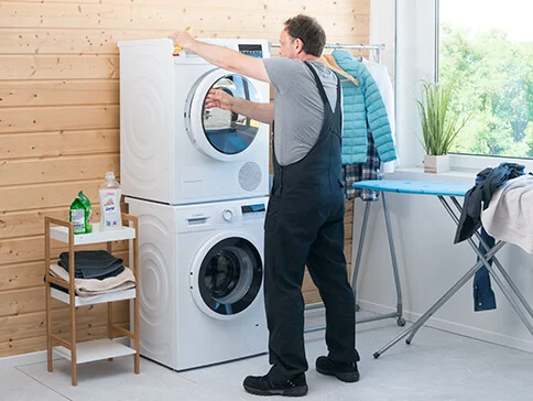 Ein Mann benutzt eine Waschmaschine und einen Trockner von Bosch.
