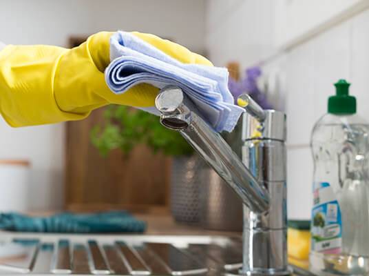 Gummihandschuhe und Reinigungstücher zum Reinigen des Wasserhahns.